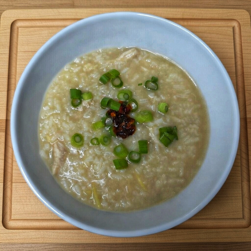 Simple ingredients for savory chicken congee on a counter — rice, ginger, chicken, broth.