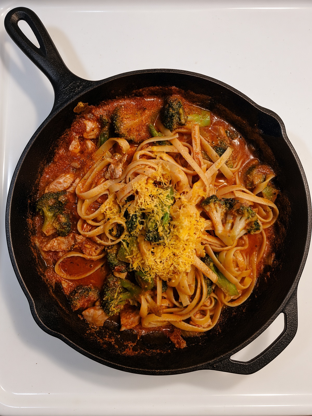 Mediterranean pork fettuccine with broccoli and pork in tomato basil sauce in a cast-iron skillet