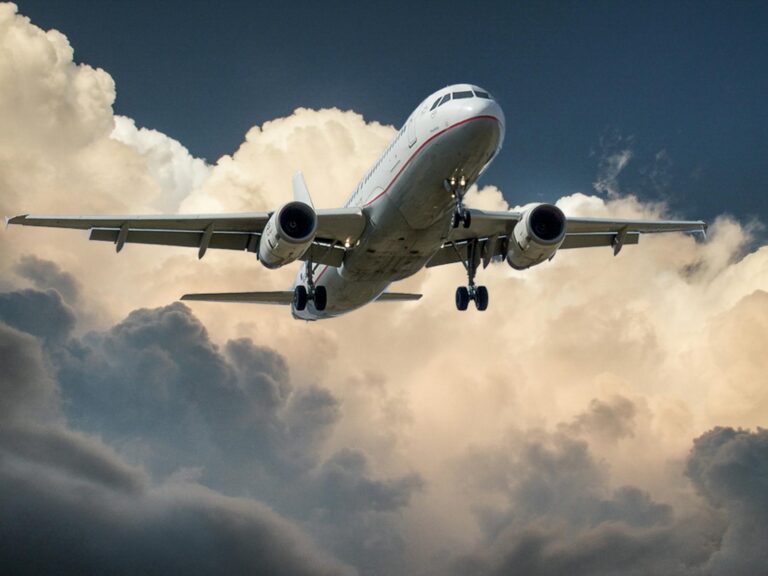 Plane movie review: a passenger jet with its landing gear down flying through dramatic clouds