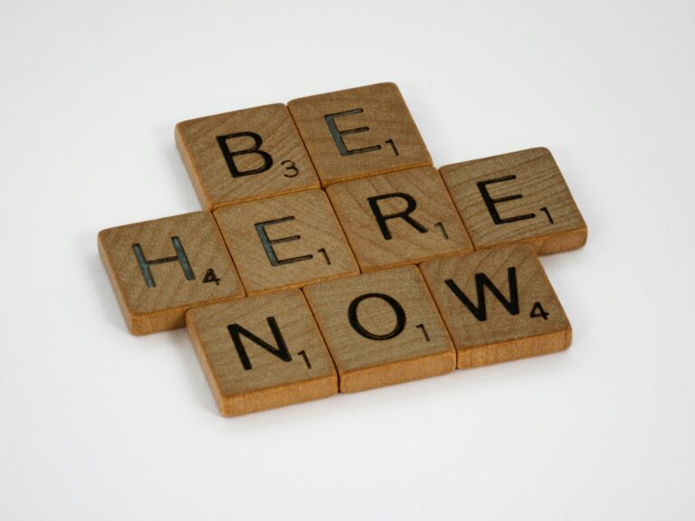 Wooden letter tiles spelling Be Here Now, illustrating The Power of Now by Eckhart Tolle
