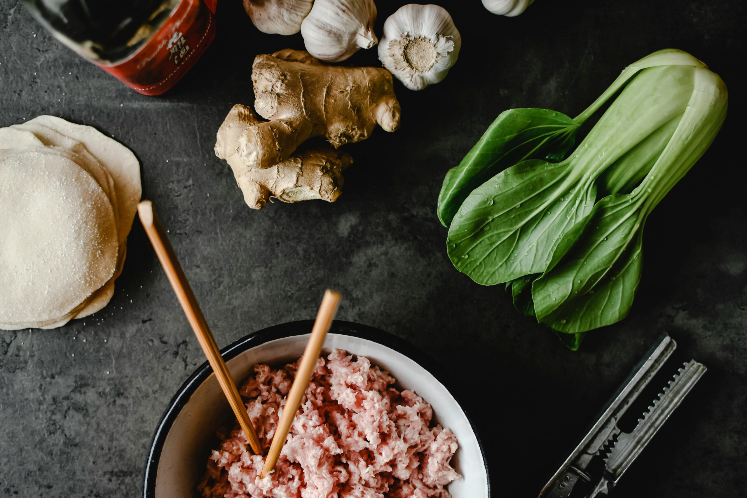 Pork and bok choy dumplings ingredients with fresh bok choy, ginger, garlic and dumpling wrappers