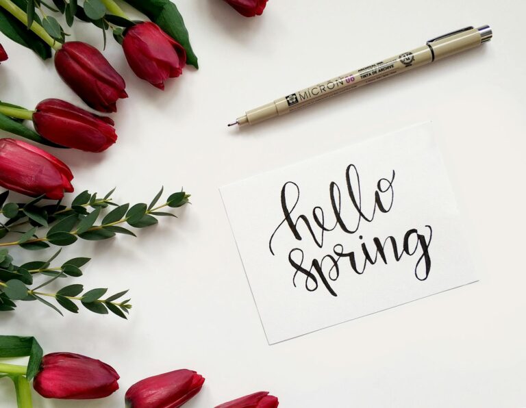 Travel essentials for a spring getaway — hello spring flat lay with tulips and a pen