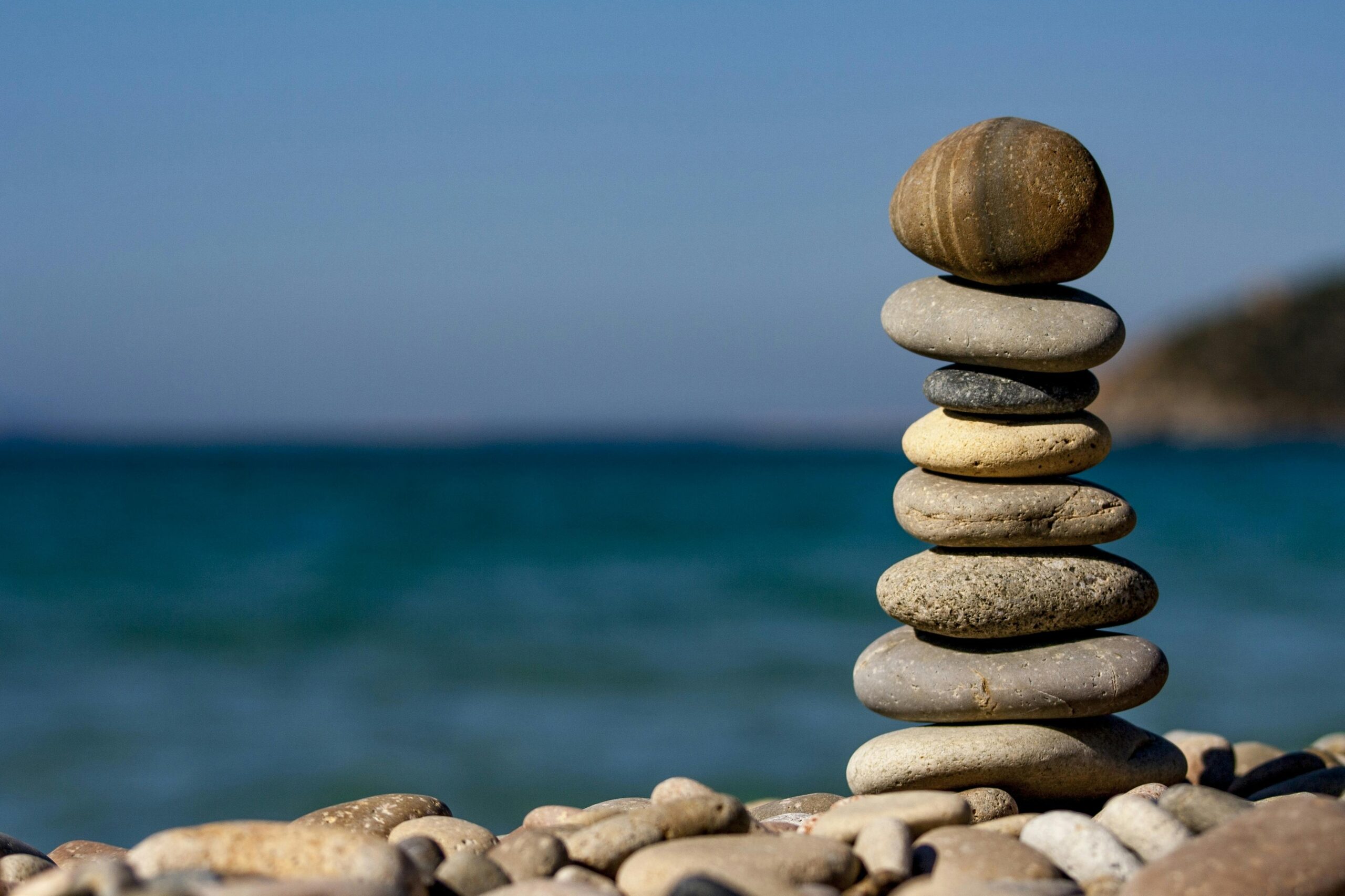 Essentialism — balanced stones by the sea, a calm reminder to focus on what truly matters