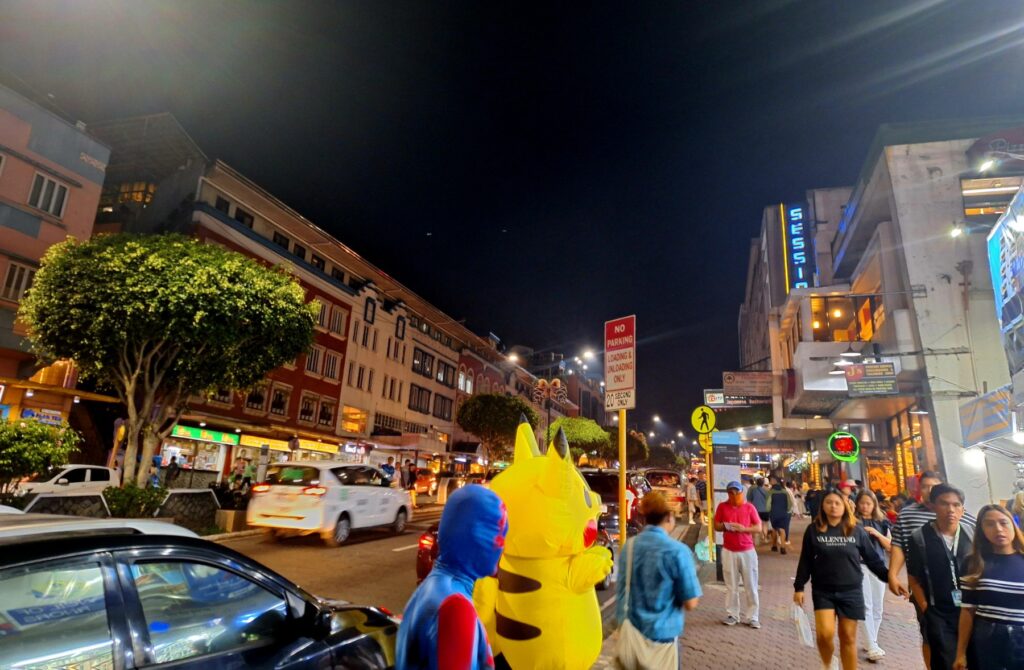 Session Road in Baguio City at night, busy with shoppers and car headlights