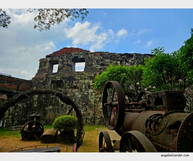 Ruined stone wall and a vintage engine in the gardens of Baluarte de San Diego, Intramuros, Manila