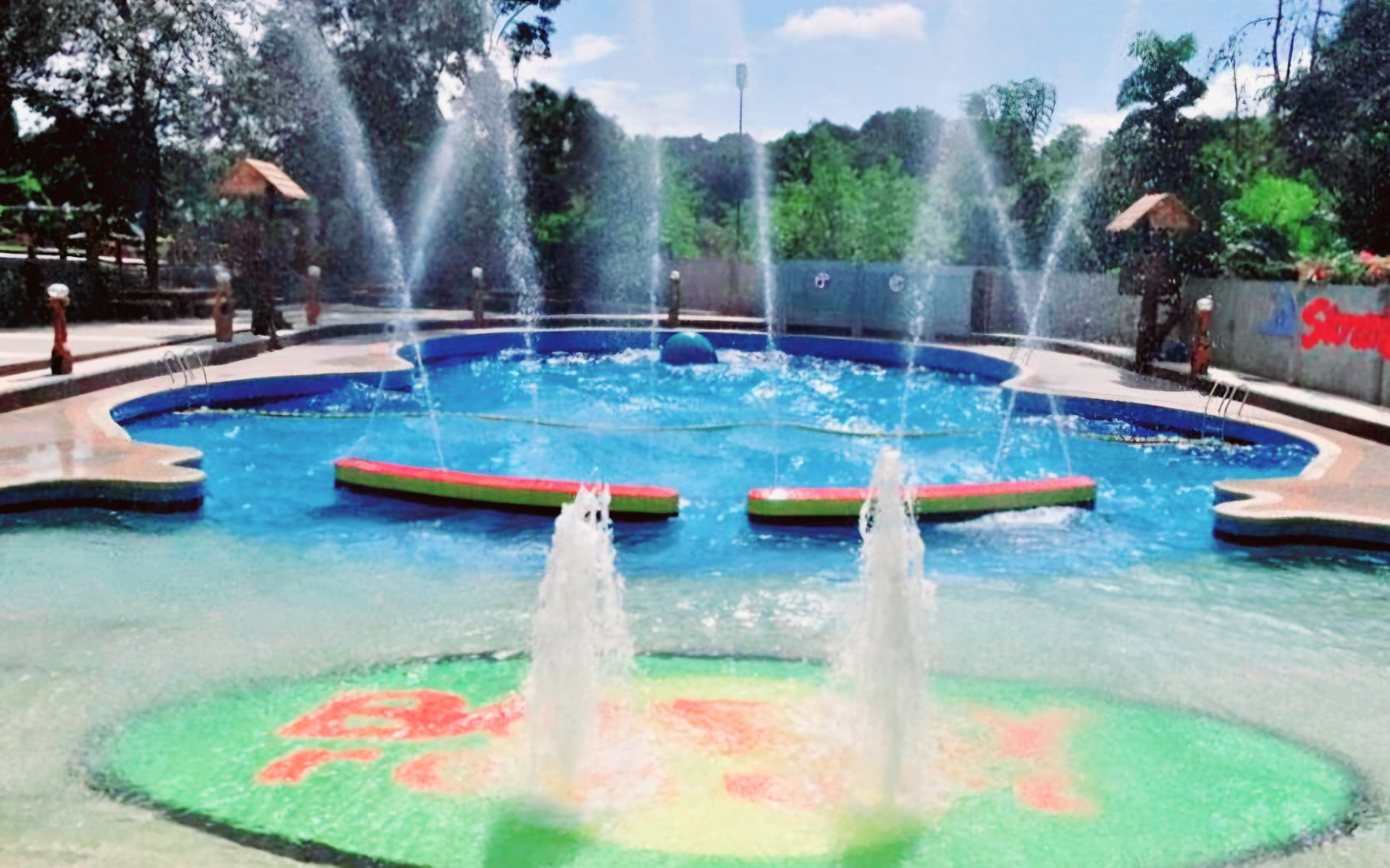 Fountain pool with water jets and Bosay Resort written on the pool floor, surrounded by palm trees at Bosay Resort Antipolo